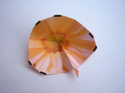 folding an orange origami flower