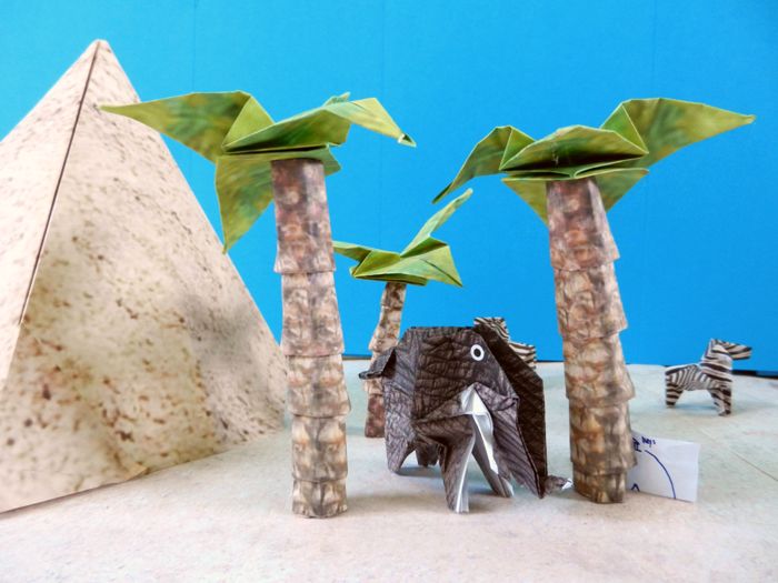 origami elephant resting under large paper palm trees origami elephant resting under large paper palm trees