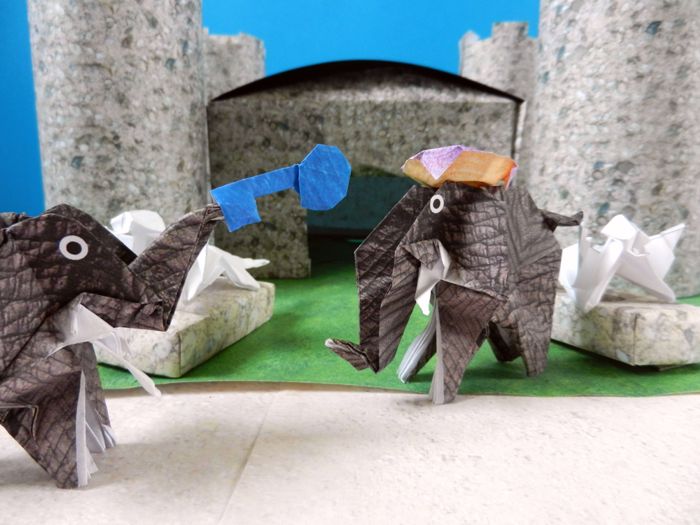 twee olifanten bij een kasteel van papier in de woestijn